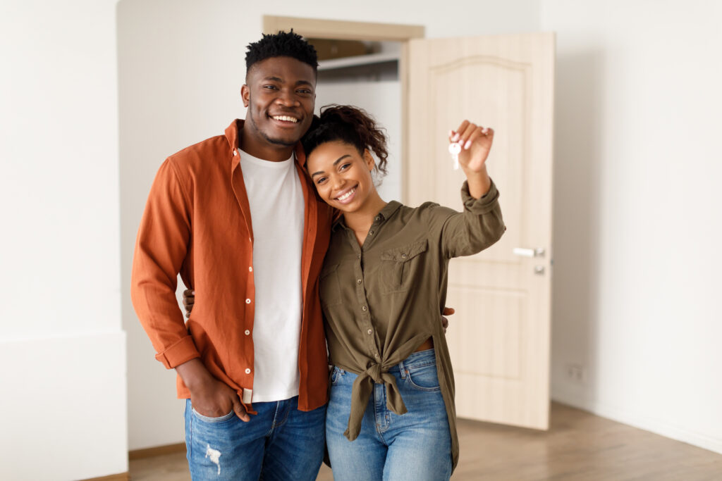 man and woman couple standing and smiling holding house keys